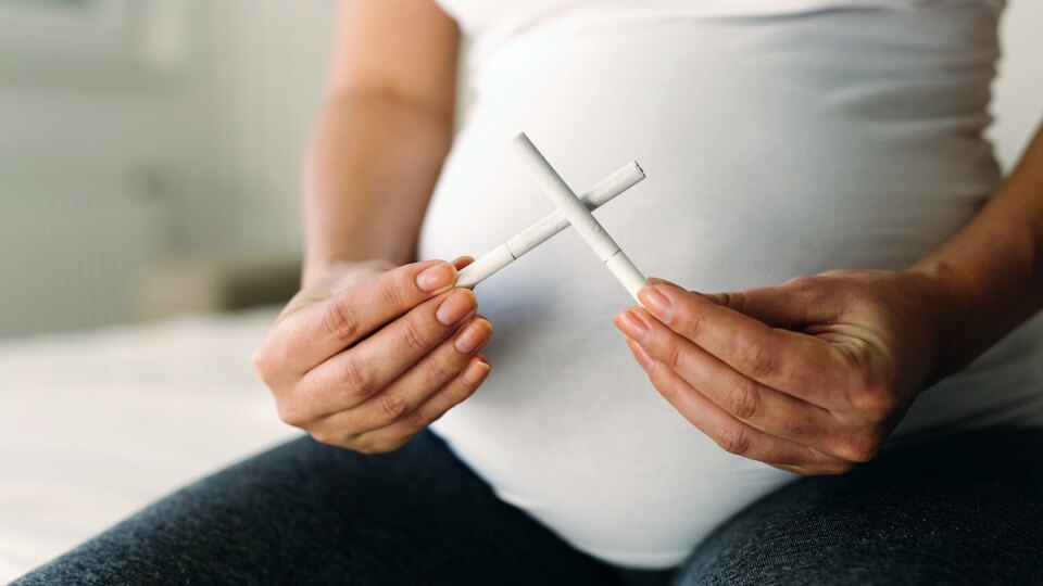 Pregnant woman holding cigarettes